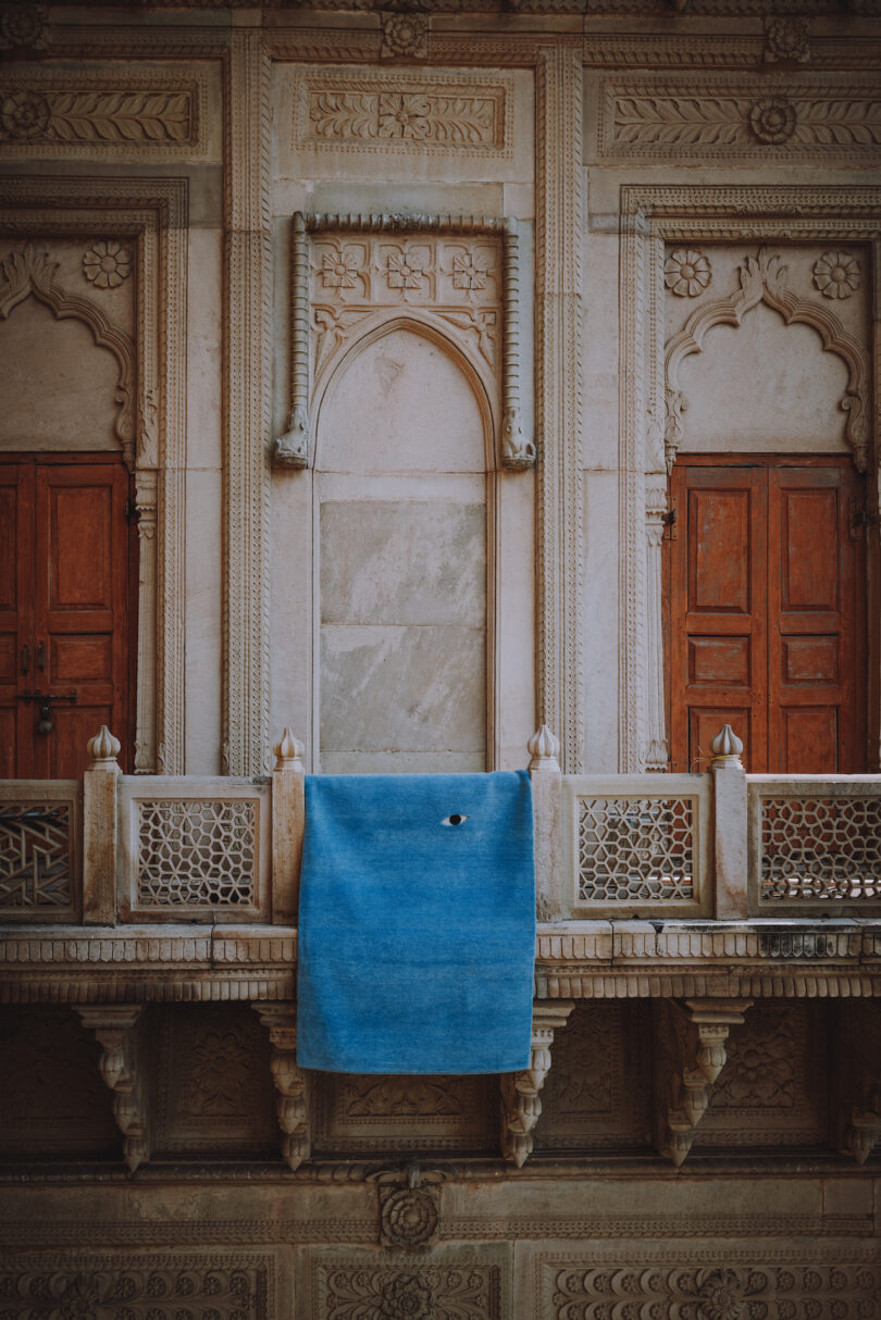 blue rug with an eye hung on balcony of a building