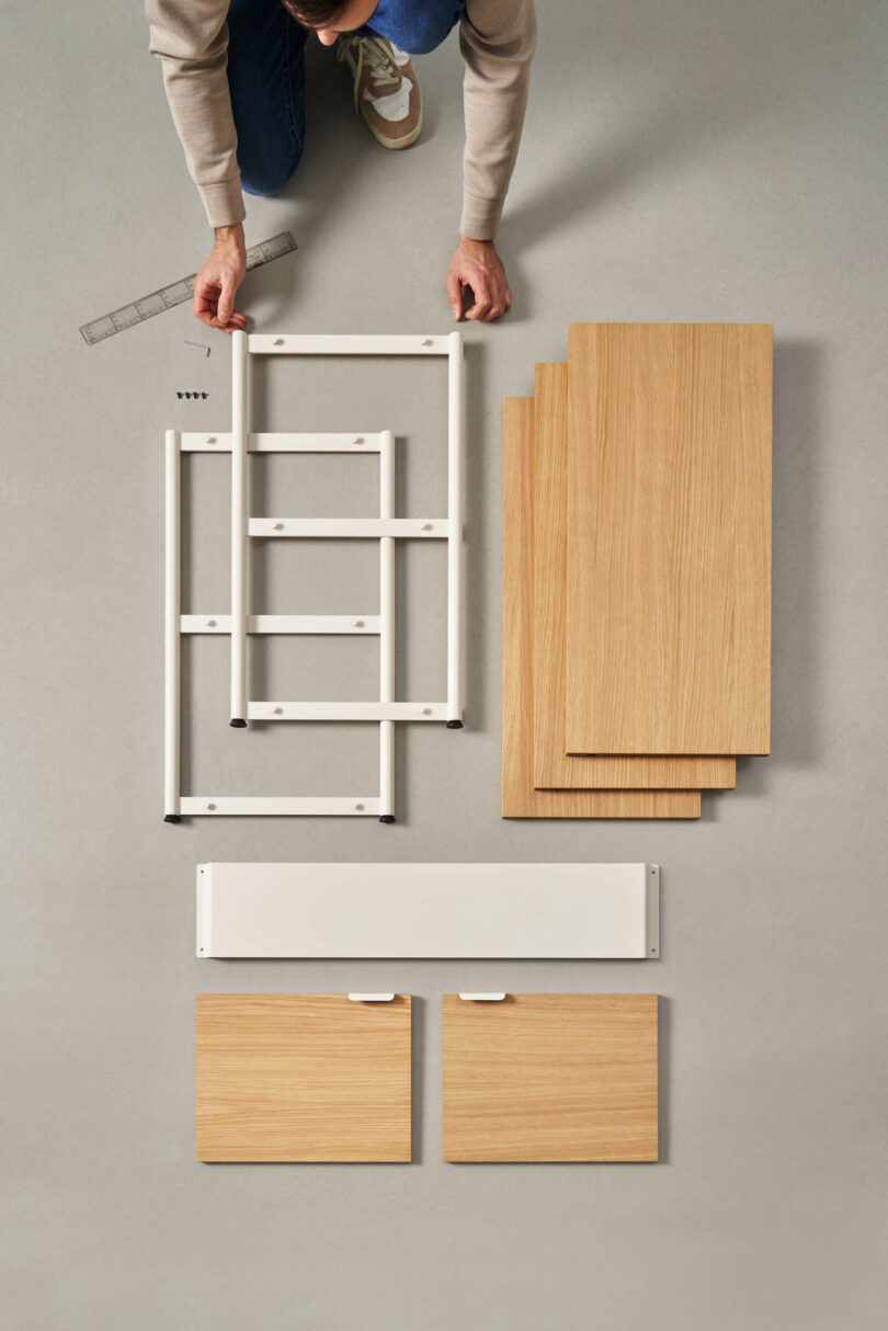 hands holding components of a modular shelving system placed on the ground