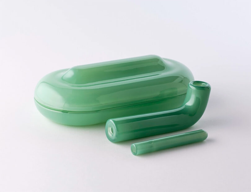 A green, translucent glass cannabis smoking pipe with a matching case, displayed against a clean white background.