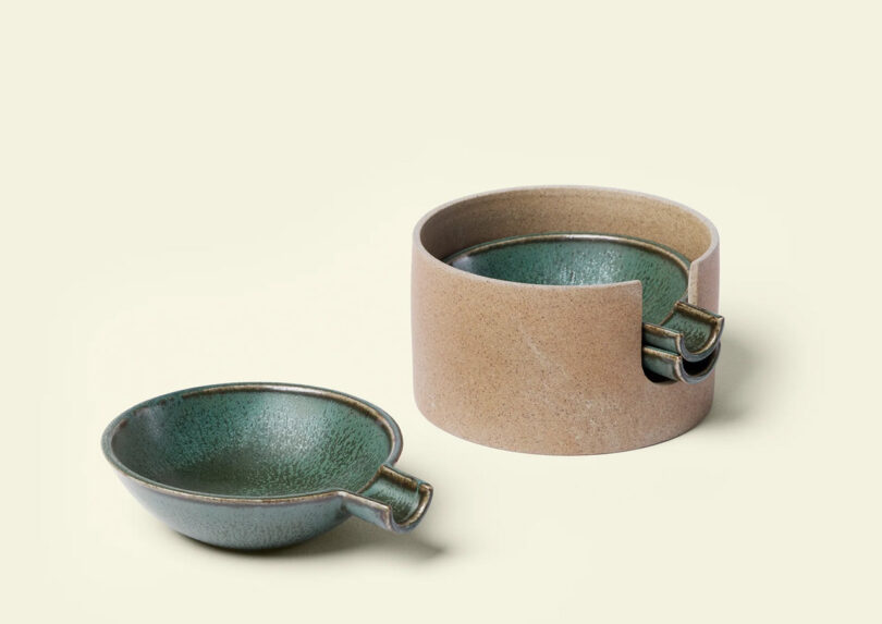 A set of 3 ceramic ashtrays with a jade green finish next to an earthen storage piece, both featuring a rustic finish with greenish interiors, against a pale background.
