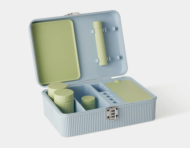 A light blue fluted exterior stash box containing three green plastic jars, one tube, a rolling tray and silicone container used for storing cannabis. A small 3 number combination lock is on the front of the opened stash box.