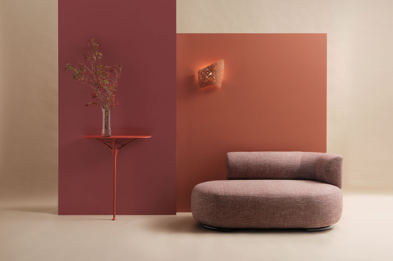 Contemporary living setup with a warm color scheme, featuring a minimalist curved couch and a matching wall console with a plant.