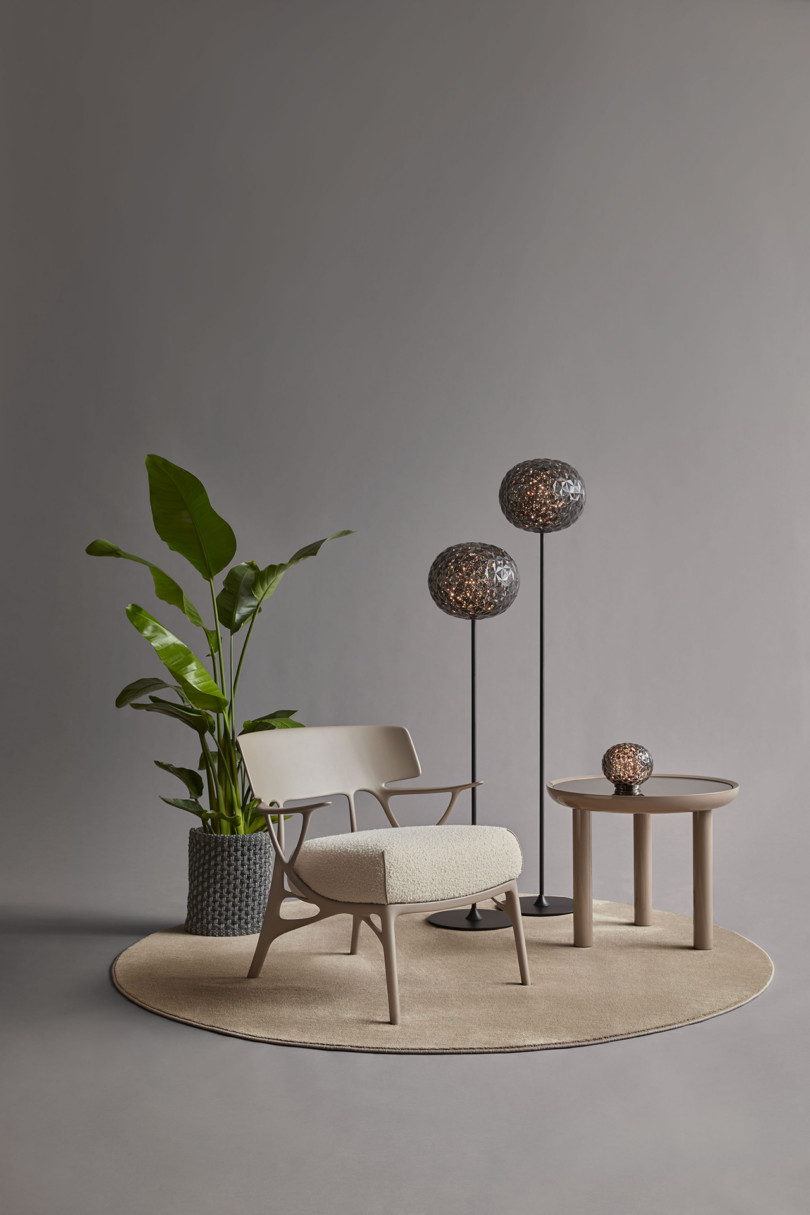 Modern interior setup with an armchair, side table, floor lamp, and a potted plant on a round rug.