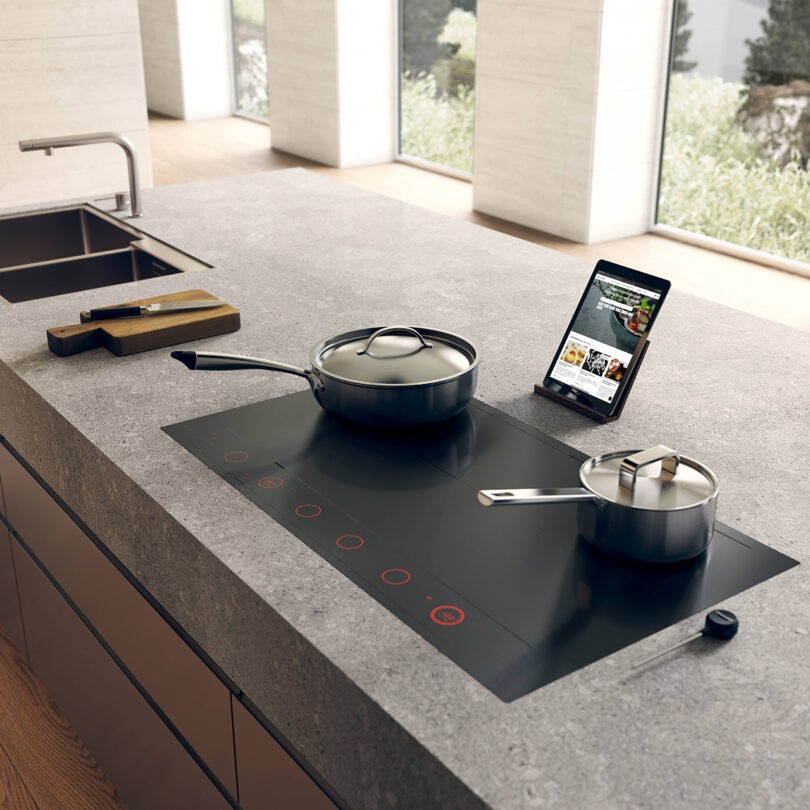 Modern kitchen with an induction cooktop and a tablet displaying a recipe.