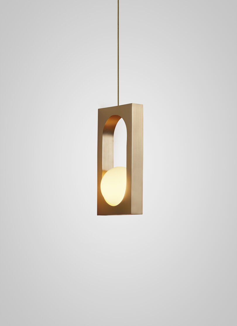 Modern pendant light with a gold and white color scheme, featuring a geometric design hanging from a cable.