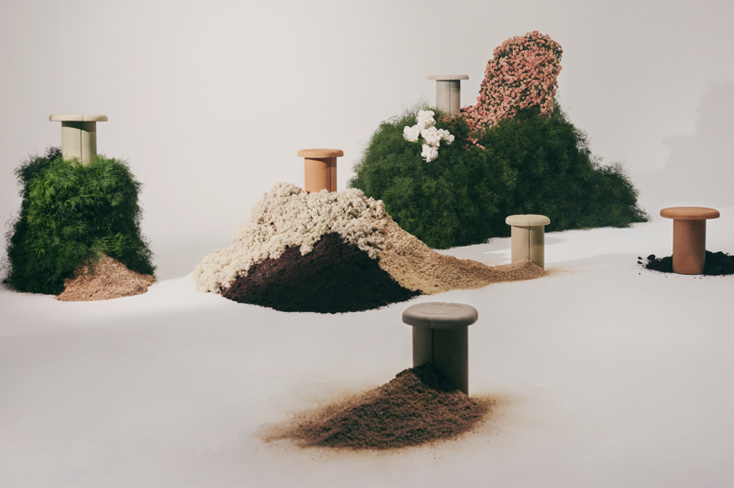 An installation featuring stools emerging from piles of variously textured materials that resemble natural elements.