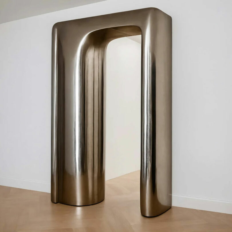 Polished bronze arch sculpture in a gallery setting.