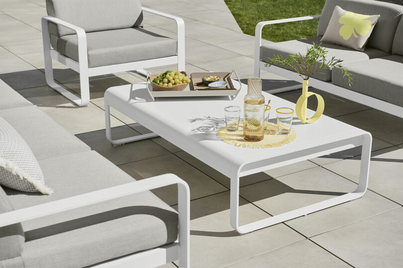 Modern outdoor furniture setup with a white coffee table and chairs on a patio.