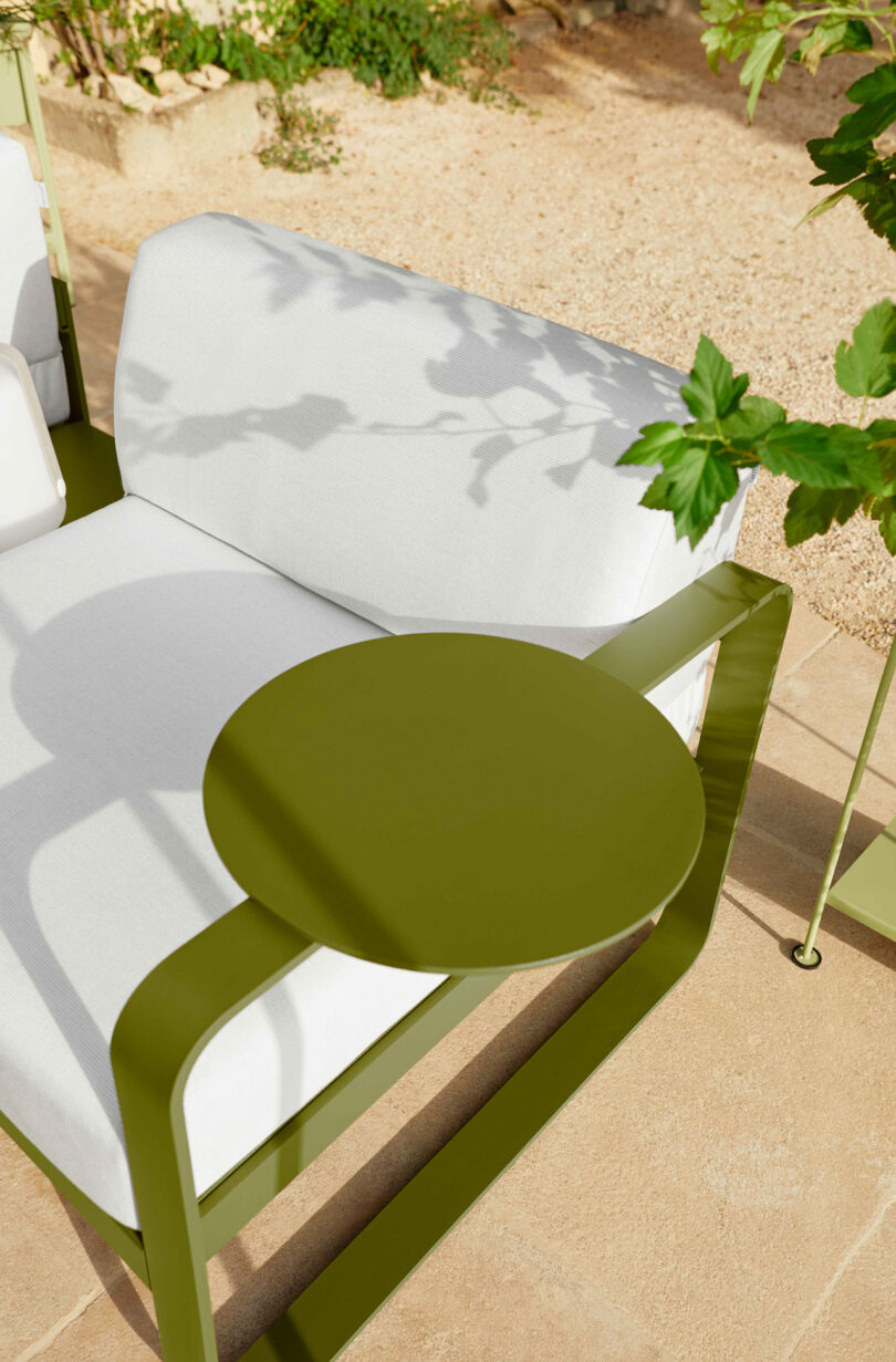 Modern green metal side table and white cushioned sofa.