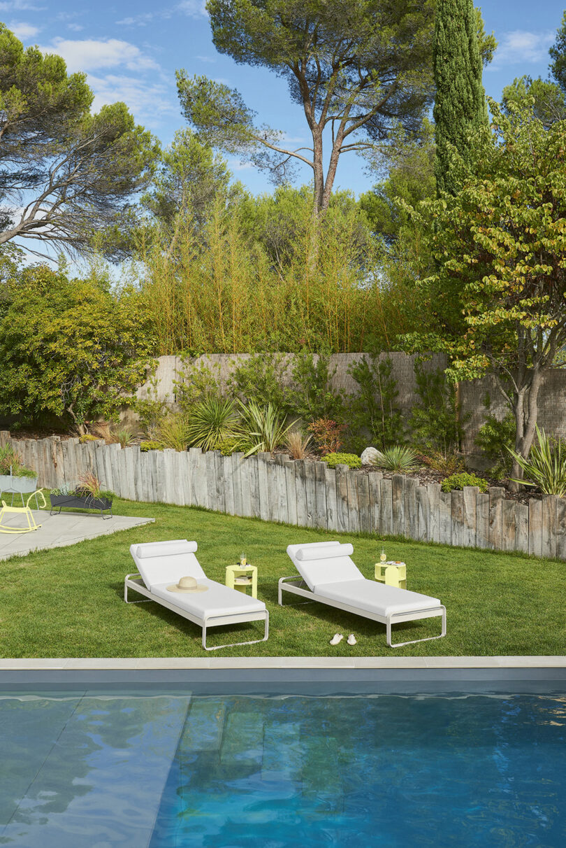 Poolside with two loungers and a lush garden backdrop.