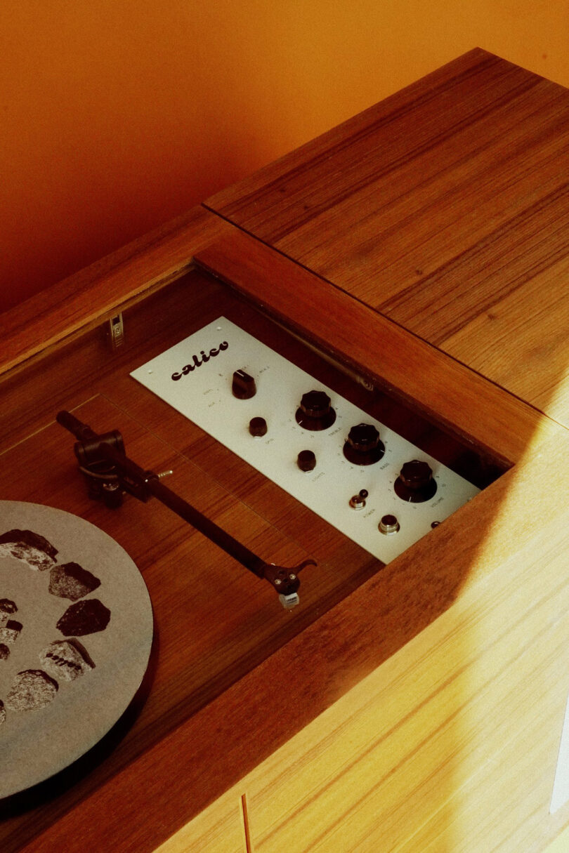 Built-in dial and switch controls set within the Calico HiFi Stereo Console turntable inset, covered by a wood and glass cover.