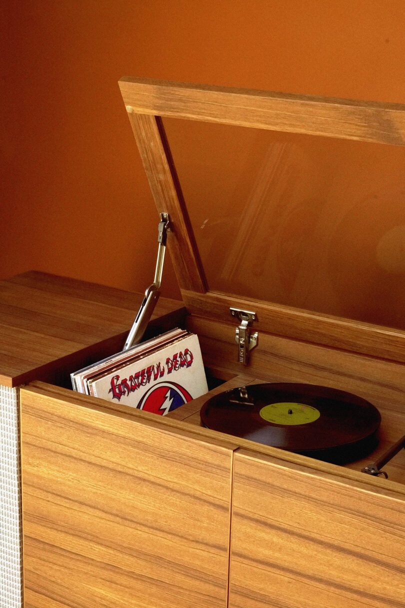 Vintage Calico HiFi Stereo Console turntable with record inside a wooden cabinet, next to a stack of vinyl albums.