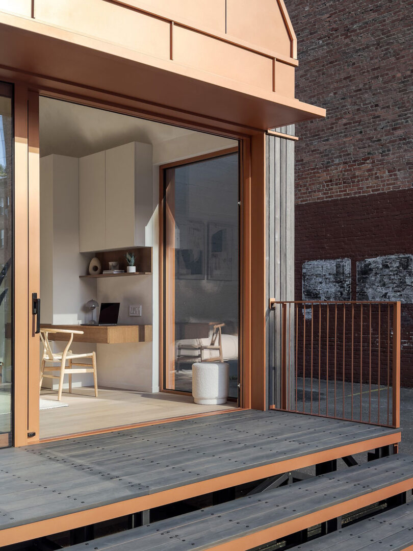 Modern urban terrace with Cosmic One ADU wooden decking and minimalist interior visible through open glass doors.