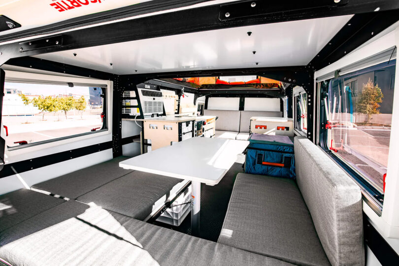 Interior of a modern Dark Sky Mantis adventure trailer with a convertible bed and dining area.