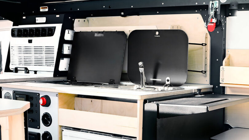 Interior of a Dark Sky Mantis adventure trailer, featuring the main galley kitchen with sink and range lids open.