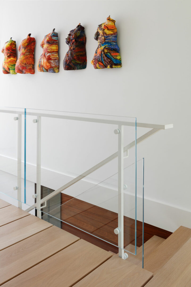A staircase with glass railings and colorful pillows on the wall.