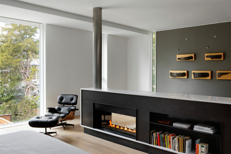 Modern living room with a fireplace, eames lounge chair, and art on the wall.