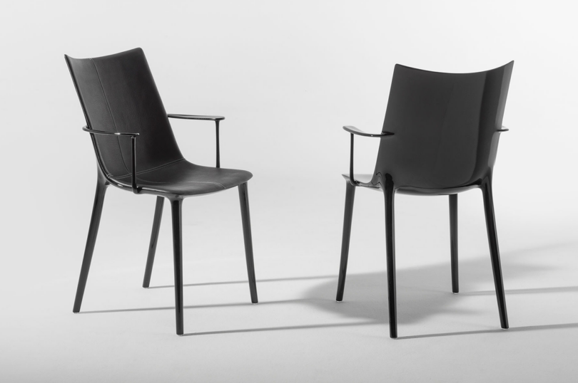 Two modern black chairs with armrests against a white background.