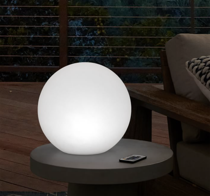 Illuminated white sphere on an outdoor table.