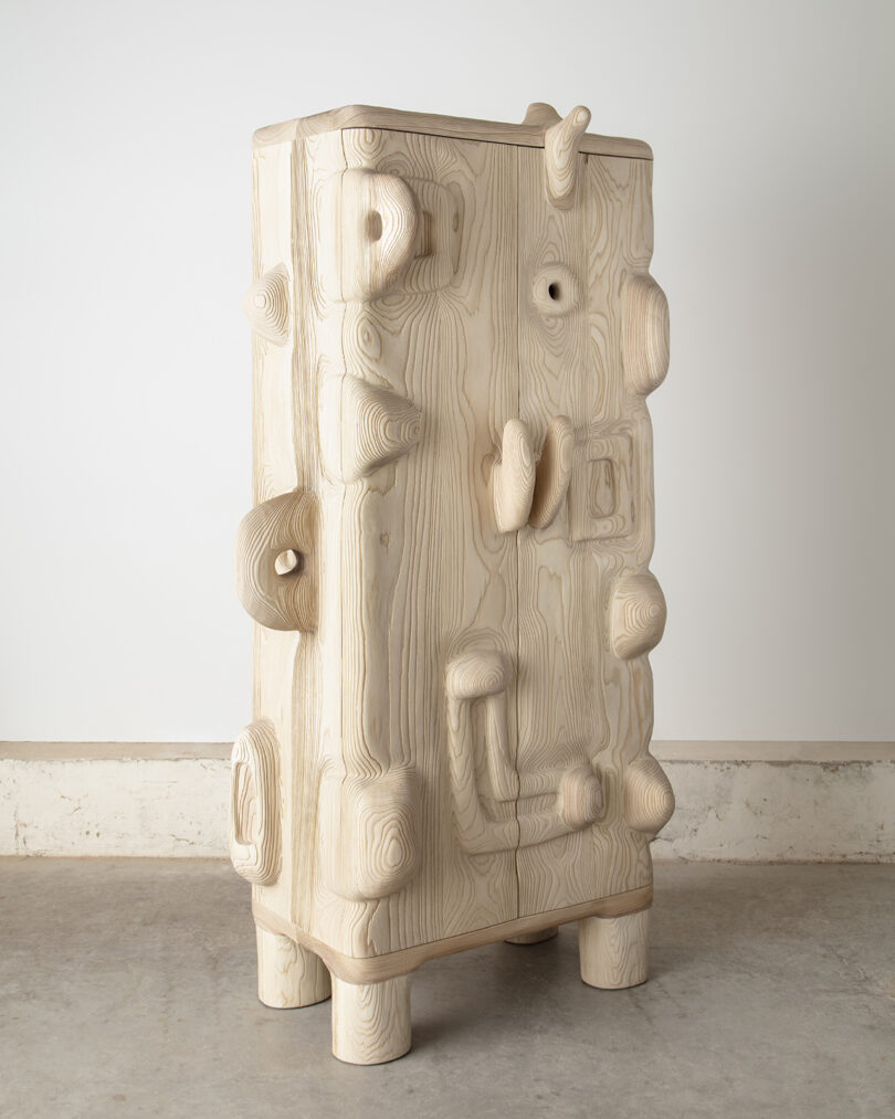 A wooden cabinet with an abstract, sculptural design featuring prominent, exaggerated wood knots and textures.