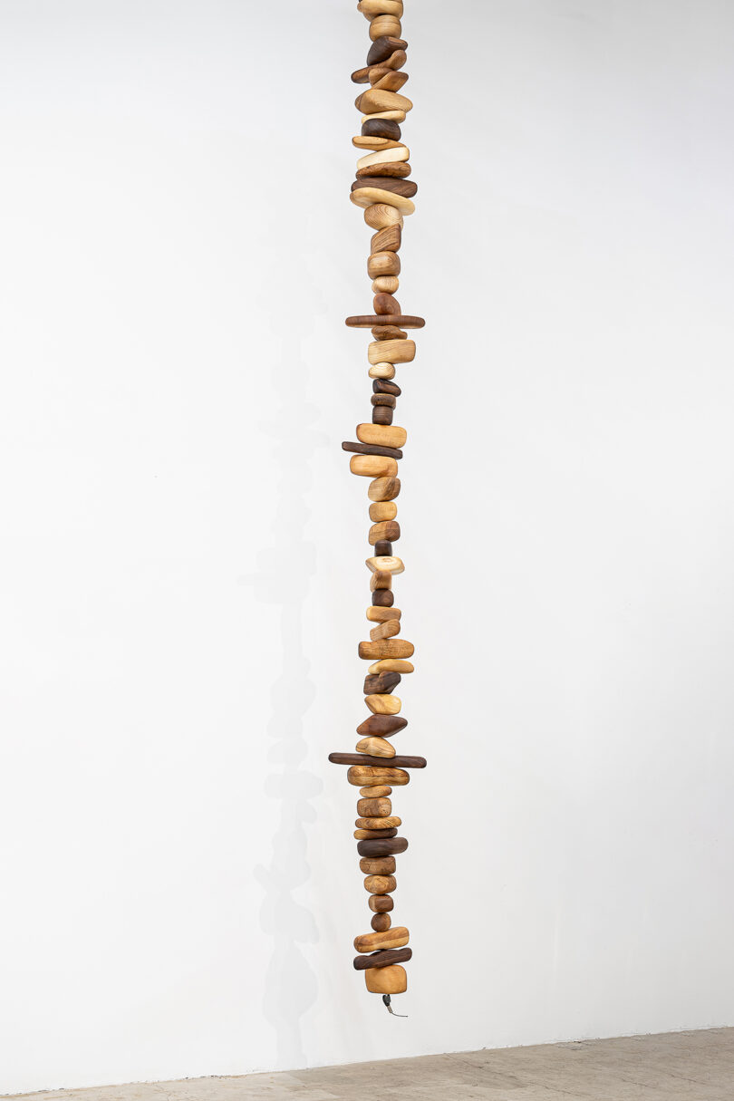 A vertical arrangement of wooden stones with different shades and grain pattern against a white background.
