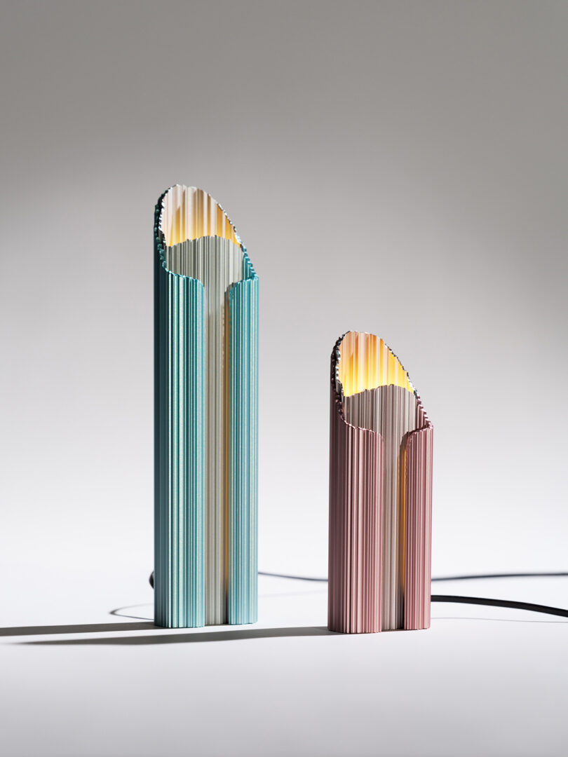 Two modern minimalist lamps standing on a plain surface against a light grey background.