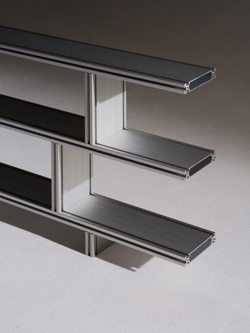 Detail of a modern three-tiered metal shelf unit on a neutral background.