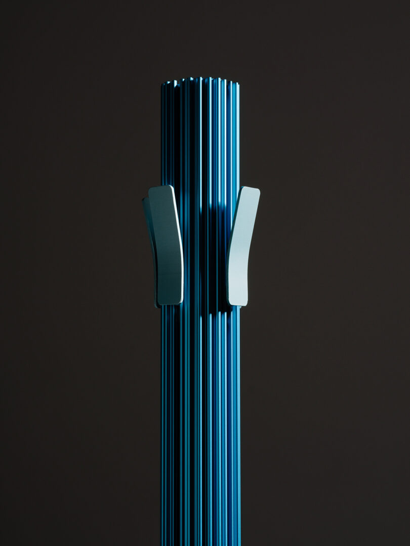 Detail of a blue modern, minimalist coat rack against a black background.