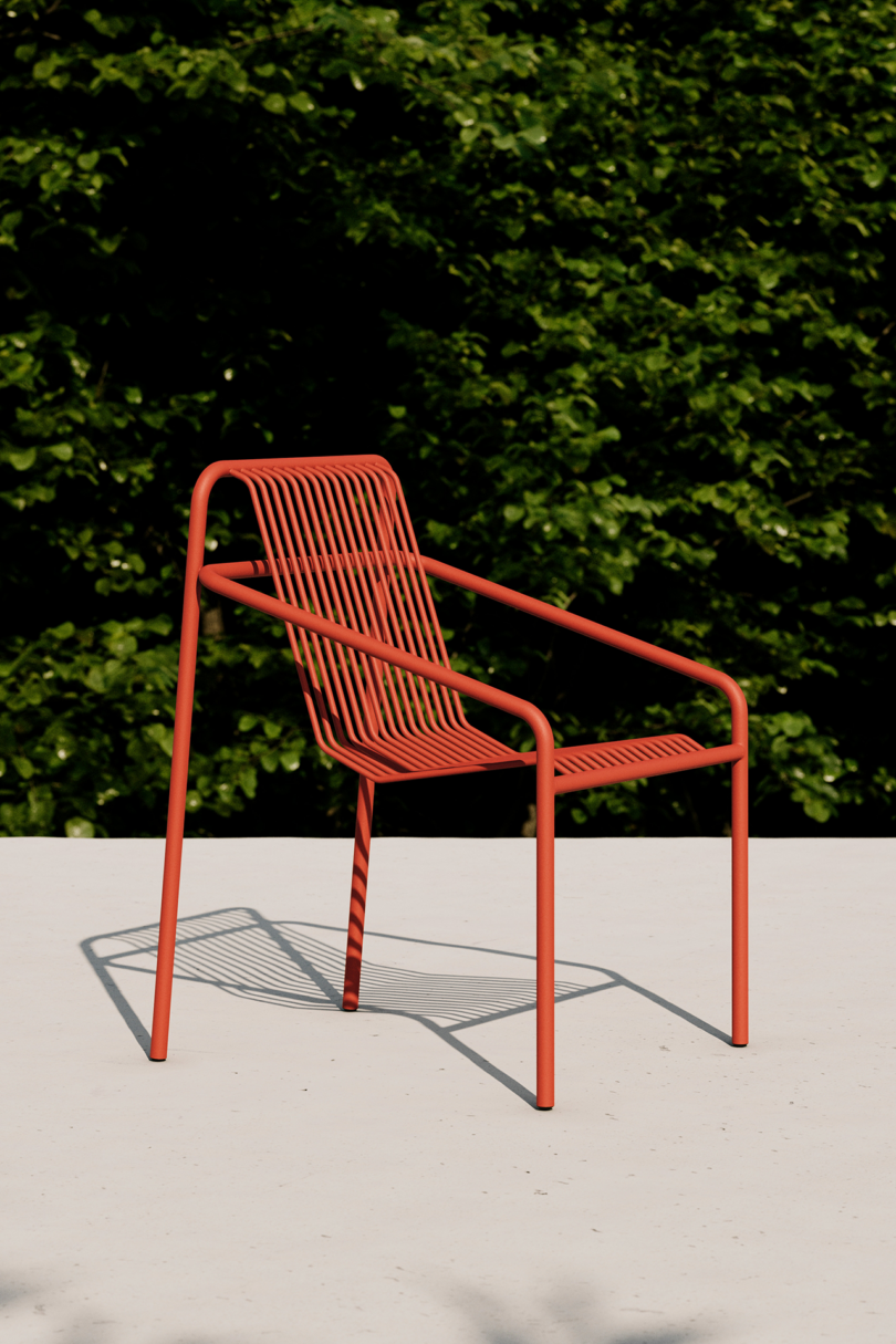 Modern red outdoor chair casting shadows in sunlight.