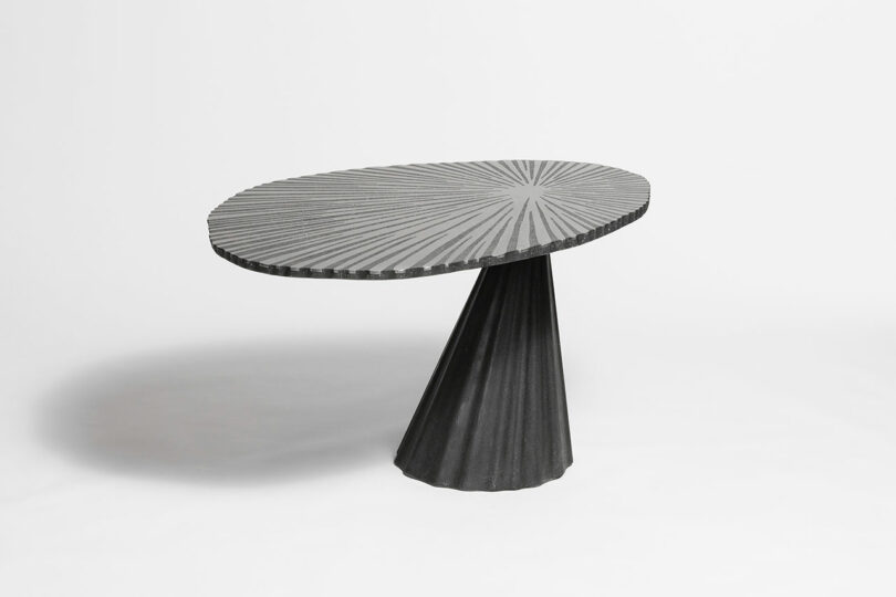 Round table with a patterned top and a conical base on a white background.