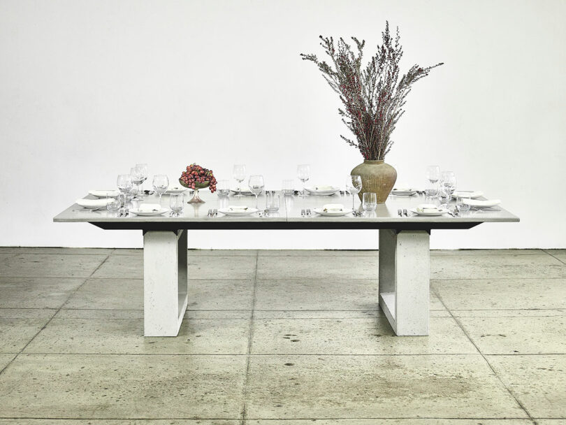Minimalistic dining table set for six with a large floral centerpiece in a modern space.