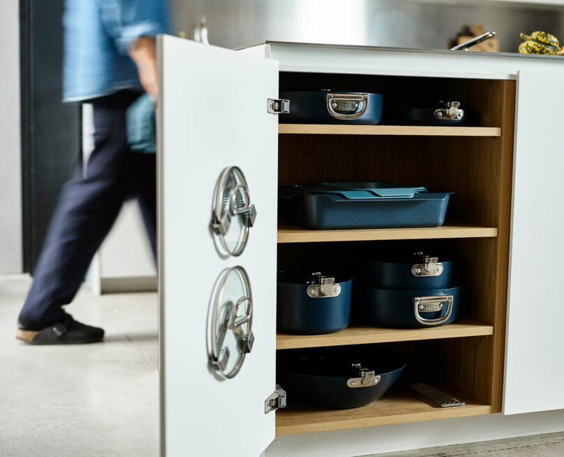 یک کابینت آشپزخانه با قفسه‌های باز، که با اندازه‌های مختلف قابلمه‌ها و تابه‌ها روی هم چیده شده است.