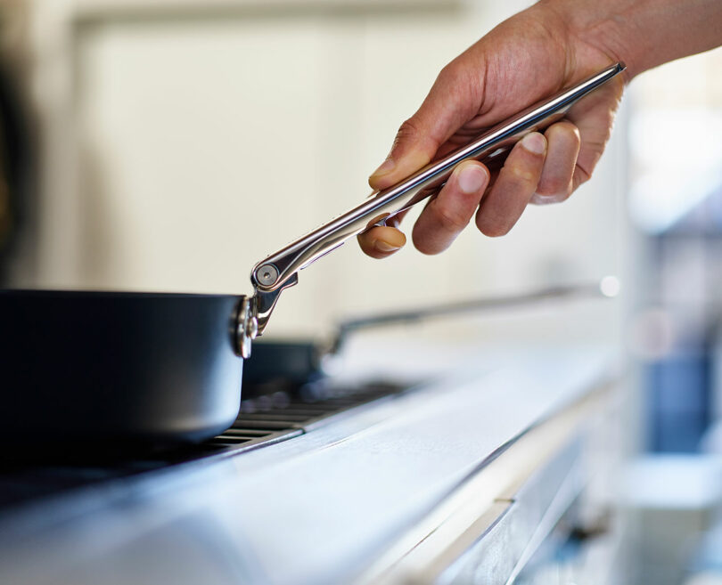 Person using tongs to cook on a stove.