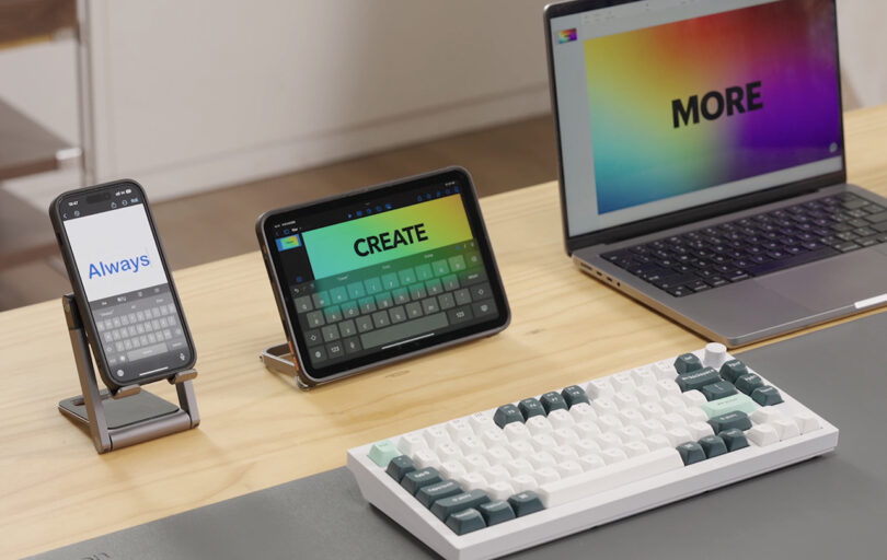 A diverse tech setup featuring a smartphone, tablet, Keychron Q1 HE mechanical keyboard, and laptop, displaying "Always Create More" across the span of each screen.