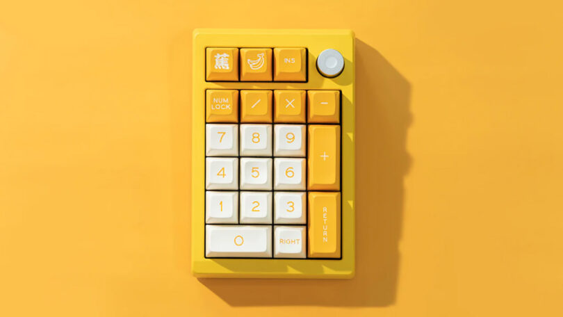 A vibrant yellow Meletrix ZoomPad Essential Edition keyboard with large white and orange keys, set against a matching yellow background.