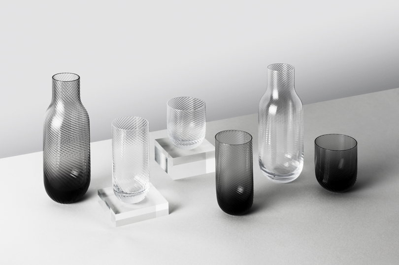 An assortment of transparent and opaque glassware with textured designs, displayed on a light surface against a neutral background.