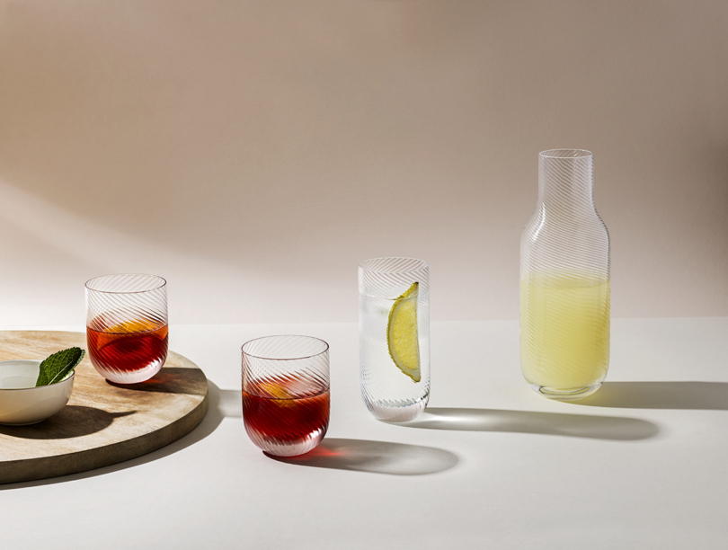 Three glasses with a red-hued beverage and a carafe of lemonade on a modern tabletop.