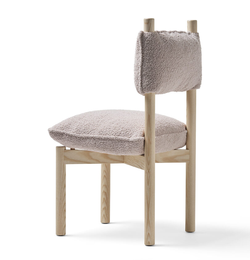 A modern wooden chair with fluffy beige upholstery on both the seat and backrest, isolated on a white background.