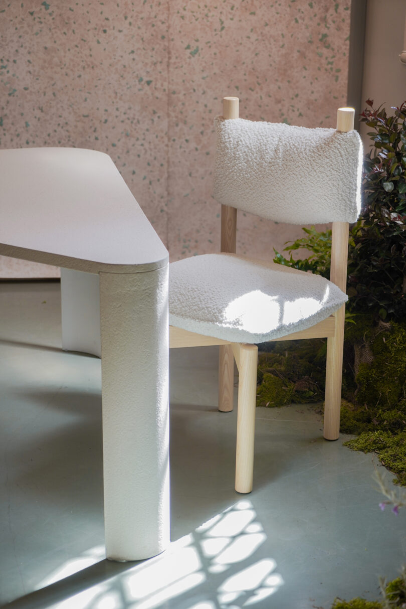 A white, fluffy chair with wooden legs beside a table.