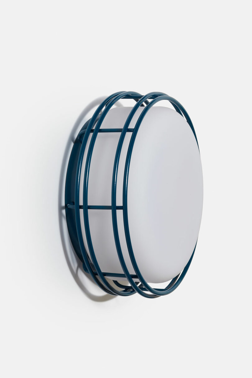 A modern wall-mounted circular mirror with a glossy blue frame, featuring geometric design elements.