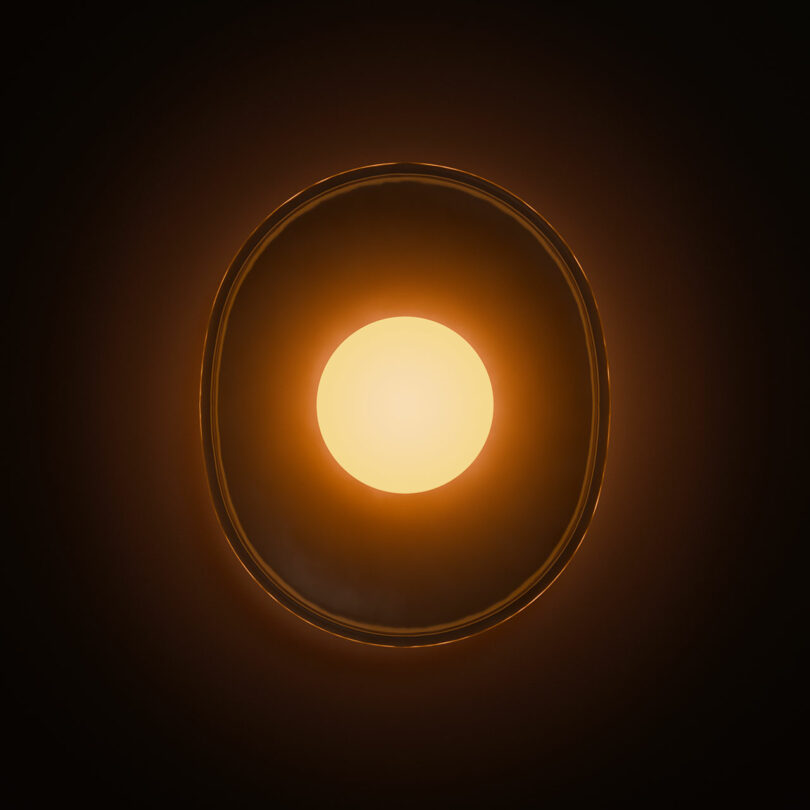 A glowing orange light with a bright center surrounded by a darker orange halo on a black background.