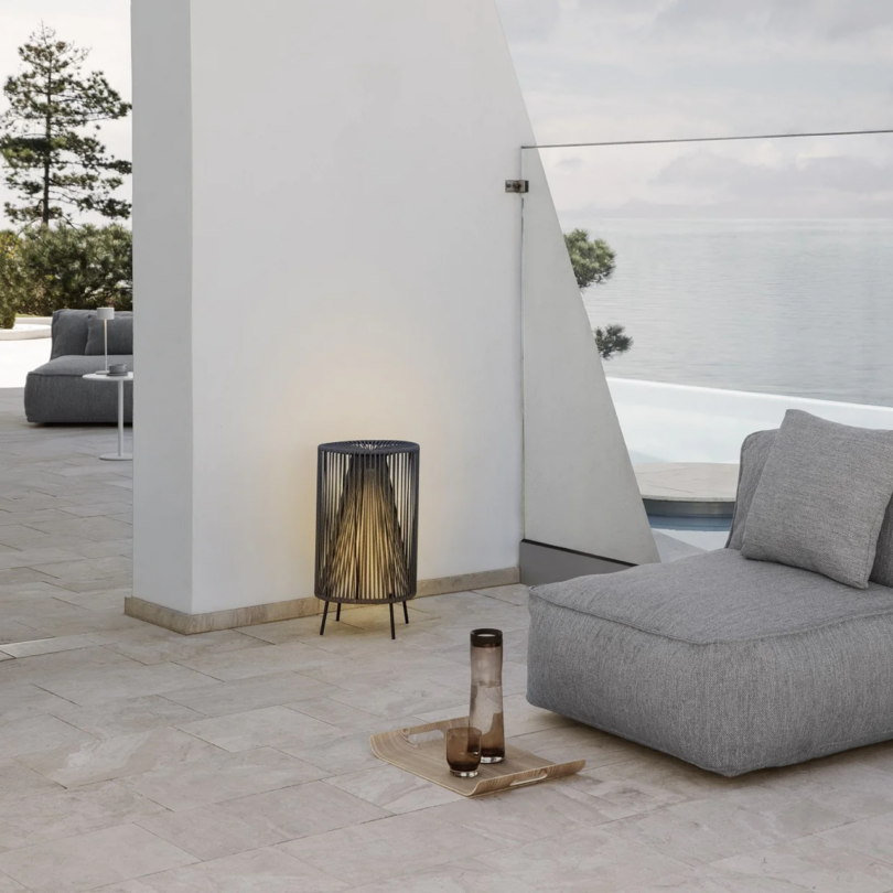 Modern outdoor lounge overlooking a tranquil sea.