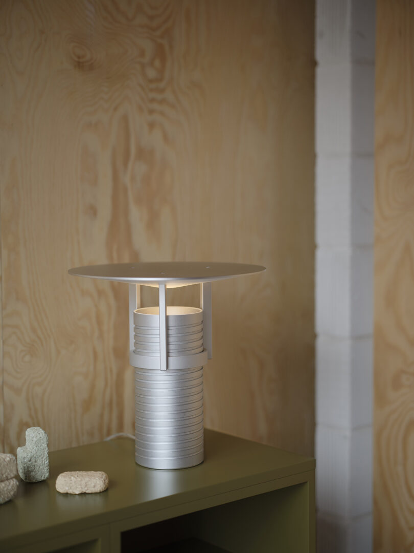 Modern adjustable metal table lamp with a cylindrical base, showcased on a styled surface.