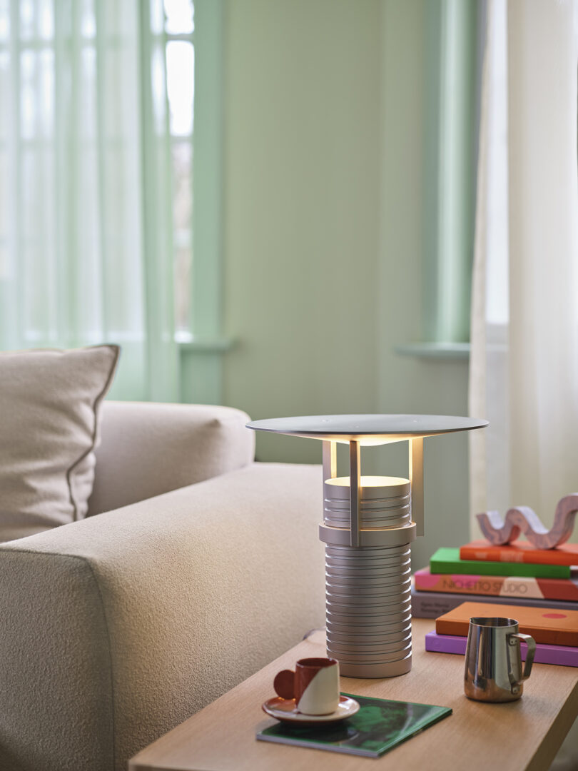 Modern adjustable metal table lamp with a cylindrical base, showcased on a styled side table.