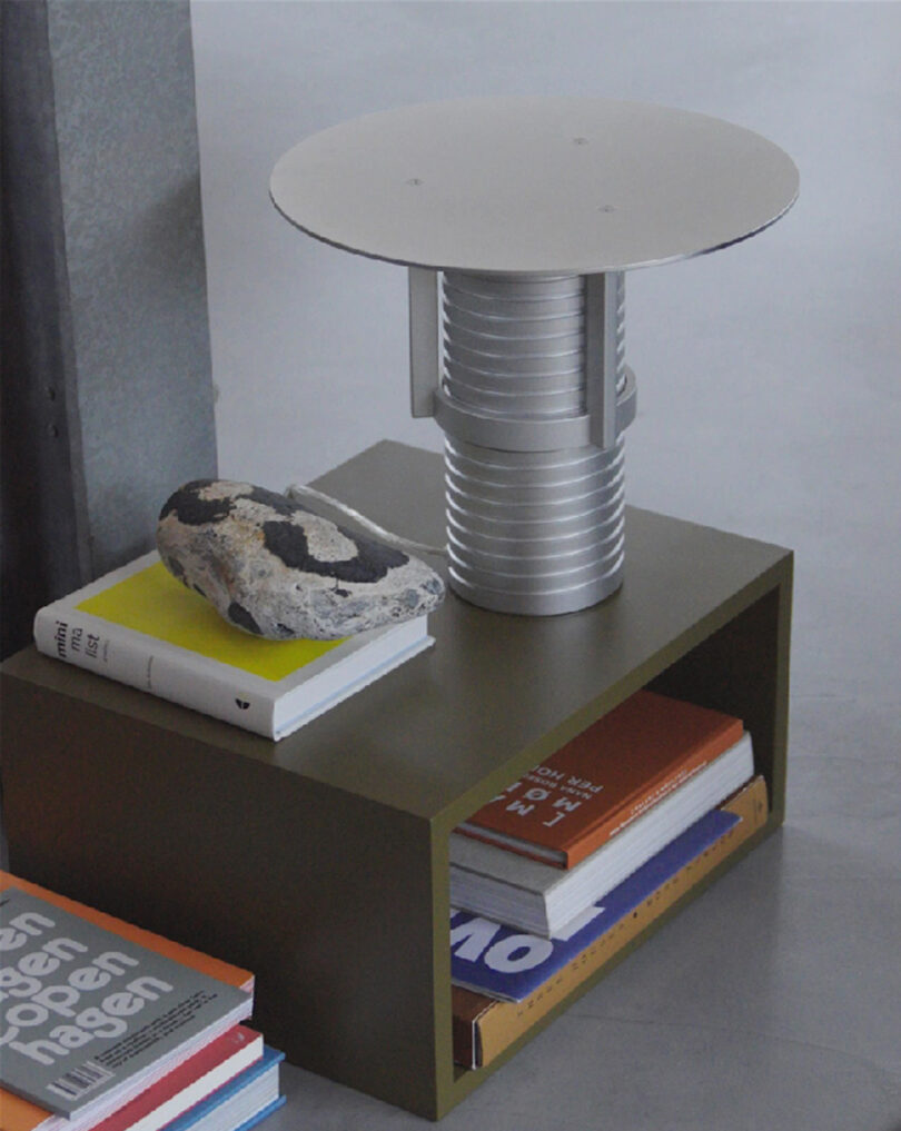 Modern adjustable metal table lamp with a cylindrical base, showcased on a styled side table.