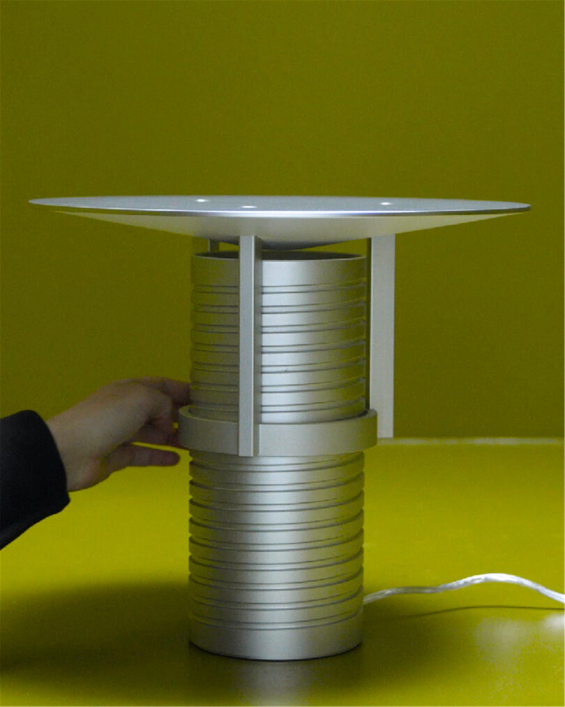 Modern adjustable metal table lamp with a cylindrical base, showcased on a styled surface.