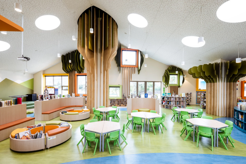 Bright and colorful children's library section with tree-shaped bookshelves and nature-inspired decor.