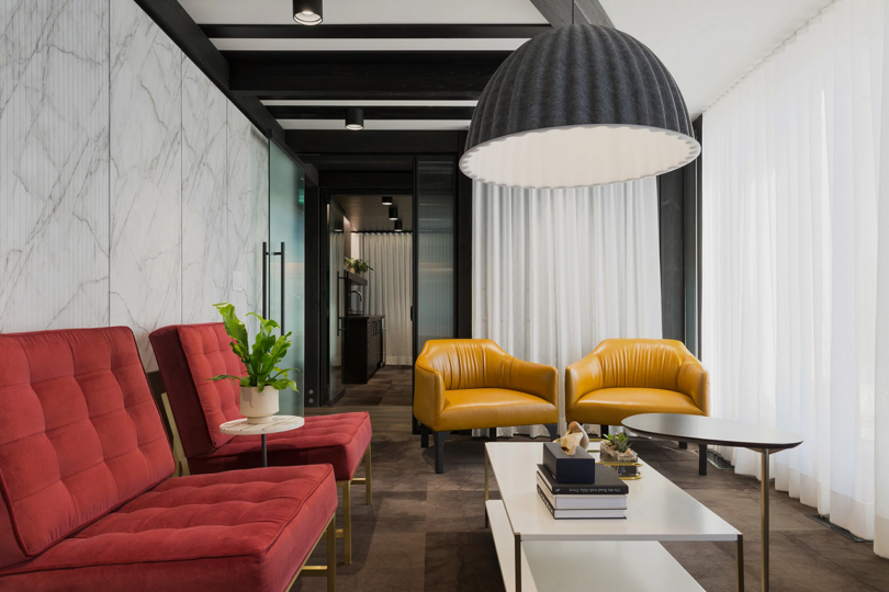 Modern office lounge with red and yellow seating and a large pendant lamp.