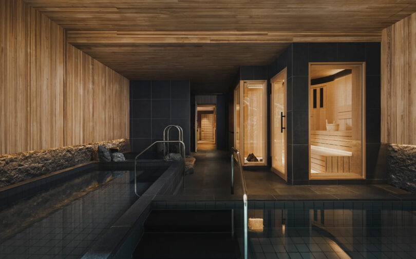 Interior of the Six Senses Kyoto hotel spa with wooden and stone walls, featuring a pool, sauna, and walkway.