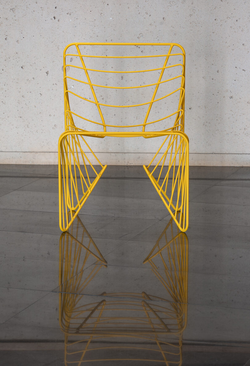 skeletal yellow chair on reflective flooring